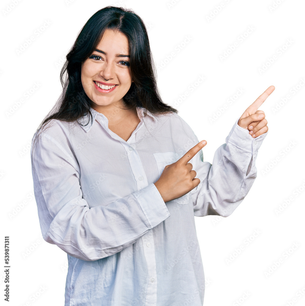 Beautiful hispanic woman wearing casual white shirt smiling and looking at the camera pointing with two hands and fingers to the side. Beautiful hispanic woman wearing casual white shirt smiling and looking at the camera pointing with two hands and fingers to the side.