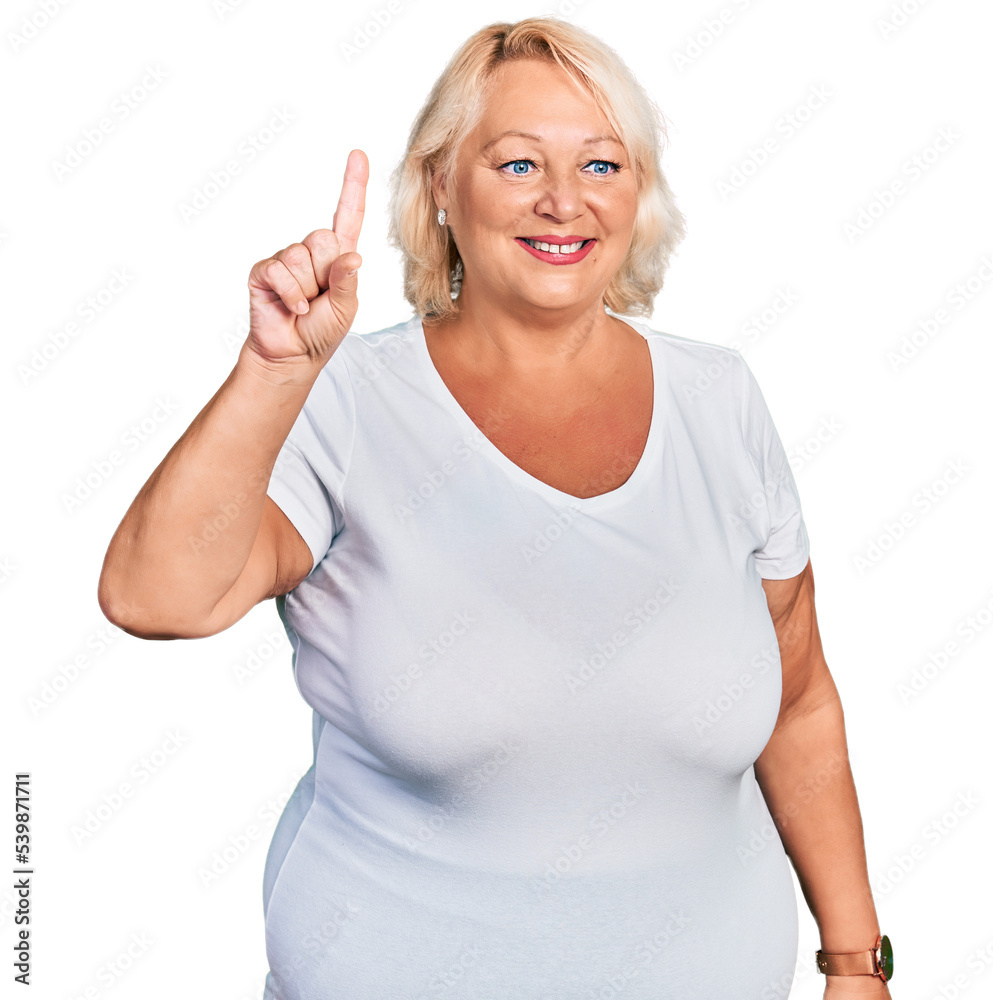 Middle age blonde woman wearing casual white t shirt showing and pointing up with finger number one while smiling confident and happy. Middle age blonde woman wearing casual white t shirt showing and pointing up with finger number one while smiling confident and happy.