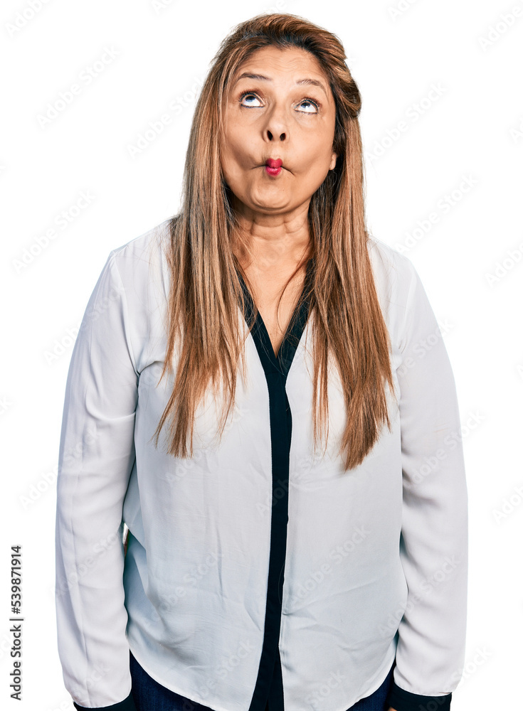 Middle age latin woman wearing business shirt making fish face with lips, crazy and comical gesture. funny expression. Middle age latin woman wearing business shirt making fish face with lips, crazy and comical gesture. funny expression.