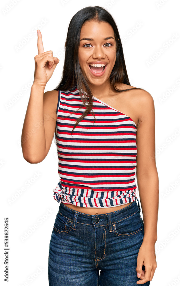 Beautiful hispanic woman wearing casual clothes pointing finger up with successful idea. exited and happy. number one. Beautiful hispanic woman wearing casual clothes pointing finger up with successful idea. exited and happy. number one.