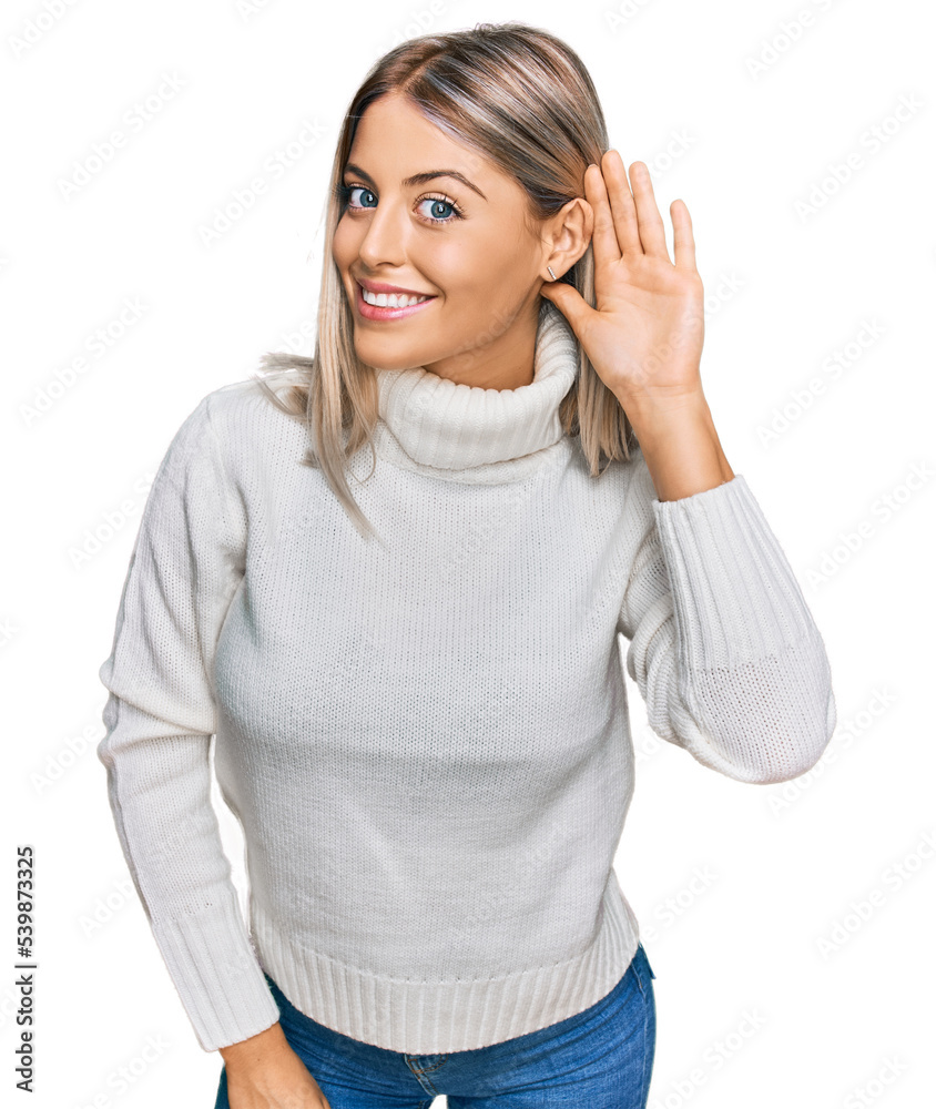 Beautiful blonde woman wearing casual turtleneck sweater smiling with hand over ear listening an hearing to rumor or gossip. deafness concept. Beautiful blonde woman wearing casual turtleneck sweater smiling with hand over ear listening an hearing to rumor or gossip. deafness concept.