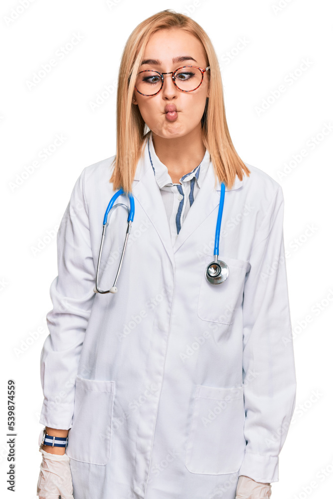 Beautiful caucasian woman wearing doctor uniform and stethoscope making fish face with lips, crazy and comical gesture. funny expression. Beautiful caucasian woman wearing doctor uniform and stethoscope making fish face with lips, crazy and comical gesture. funny expression.