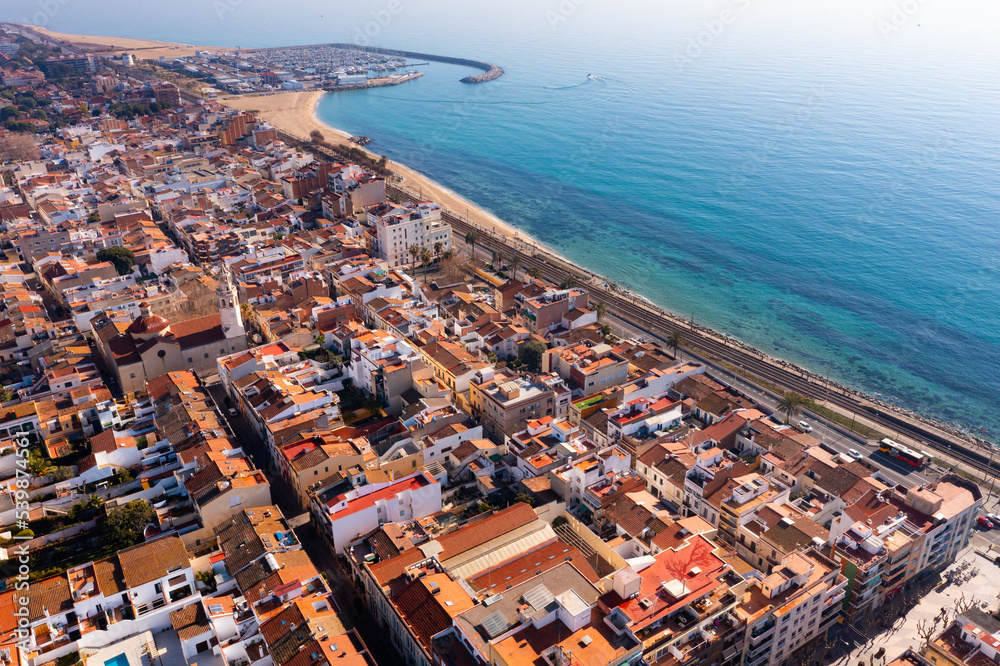 Scenic drone view of seaside areas of Catalan city of Premia de Mar with modern residential buildings and port with moored yachts on sunny winter day, Spain - obrazy, fototapety, plakaty 