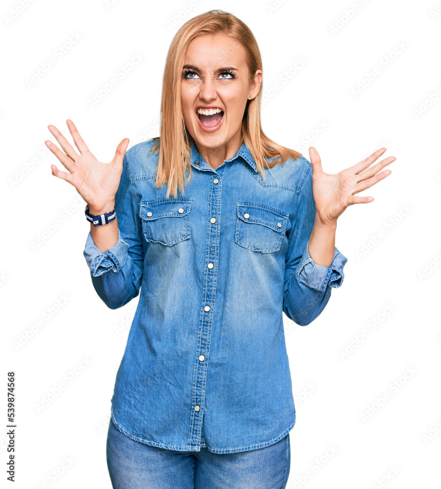 Beautiful caucasian woman wearing casual denim jacket crazy and mad shouting and yelling with aggressive expression and arms raised. frustration concept. Beautiful caucasian woman wearing casual denim jacket crazy and mad shouting and yelling with aggressive expression and arms raised. frustration concept.