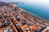 Scenic drone view of seaside areas of Catalan city of Premia de Mar with modern residential buildings and port with moored yachts on sunny winter day, Spain