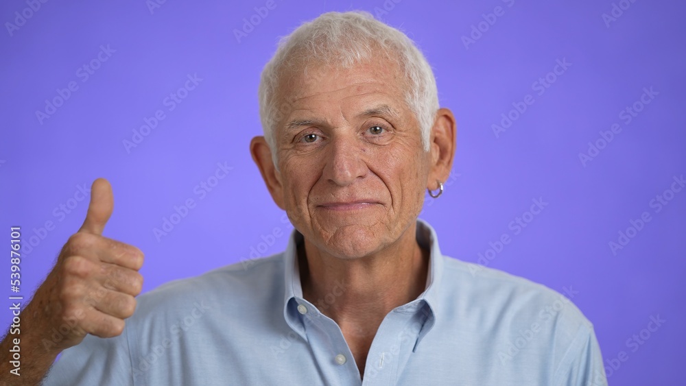 Closeup portrait of smiling happy elderly mature man giving thumbs up on solid purple background. Closeup portrait of smiling happy elderly mature man giving thumbs up on solid purple background.