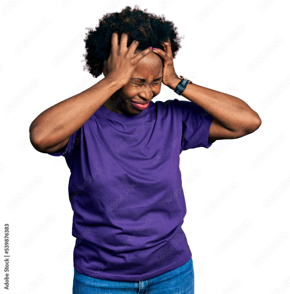 African american woman with afro hair wearing casual purple t shirt suffering from headache desperate and stressed because pain and migraine. hands on head. African american woman with afro hair wearing casual purple t shirt suffering from headache desperate and stressed because pain and migraine. hands on head.