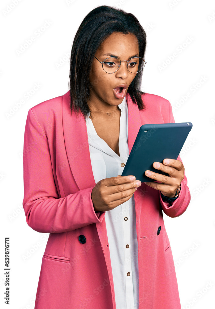 Beautiful hispanic woman using touchpad device scared and amazed with open mouth for surprise, disbelief face Beautiful hispanic woman using touchpad device scared and amazed with open mouth for surprise, disbelief face