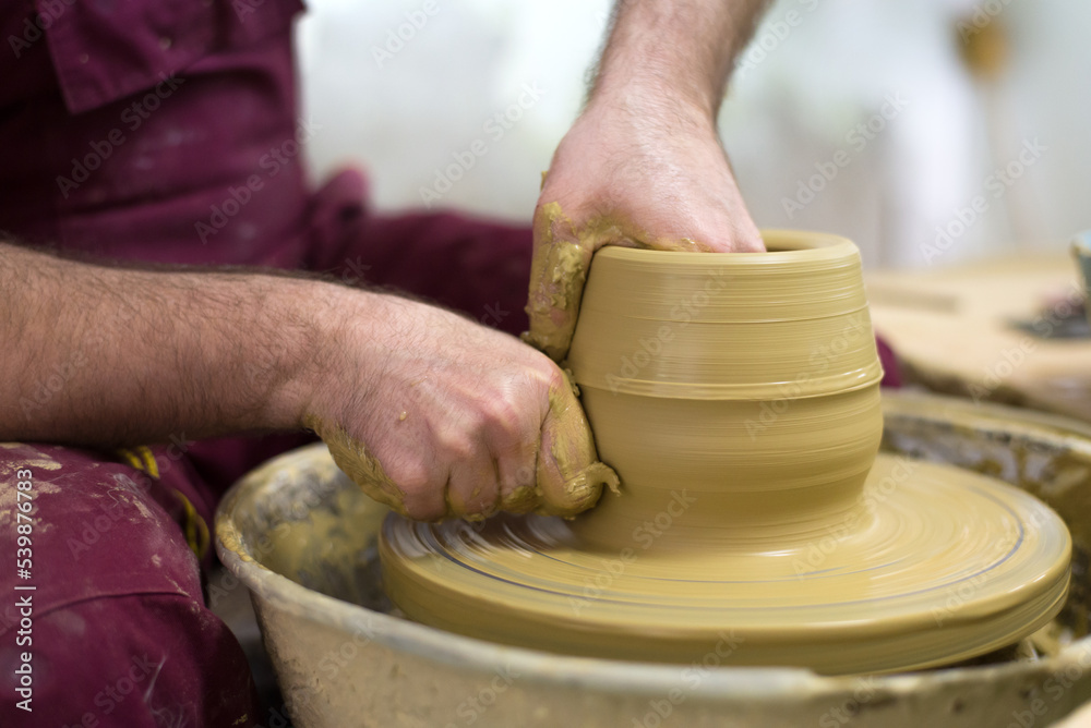 Man professional potter making pottery from wet clay in his pottery workshop