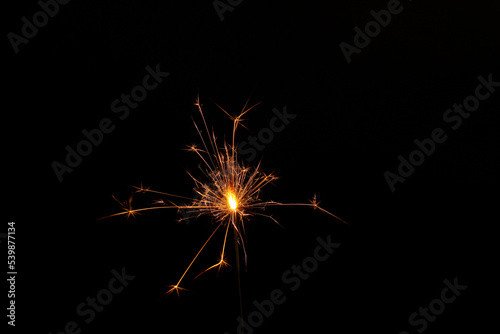 One burning sparkler stick on black background