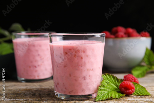 Tasty raspberry smoothie and fresh berries on wooden table, closeup