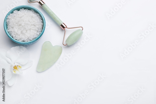 Gua sha stone  face roller  bath salt and orchid flower on white background  flat lay. Space for text