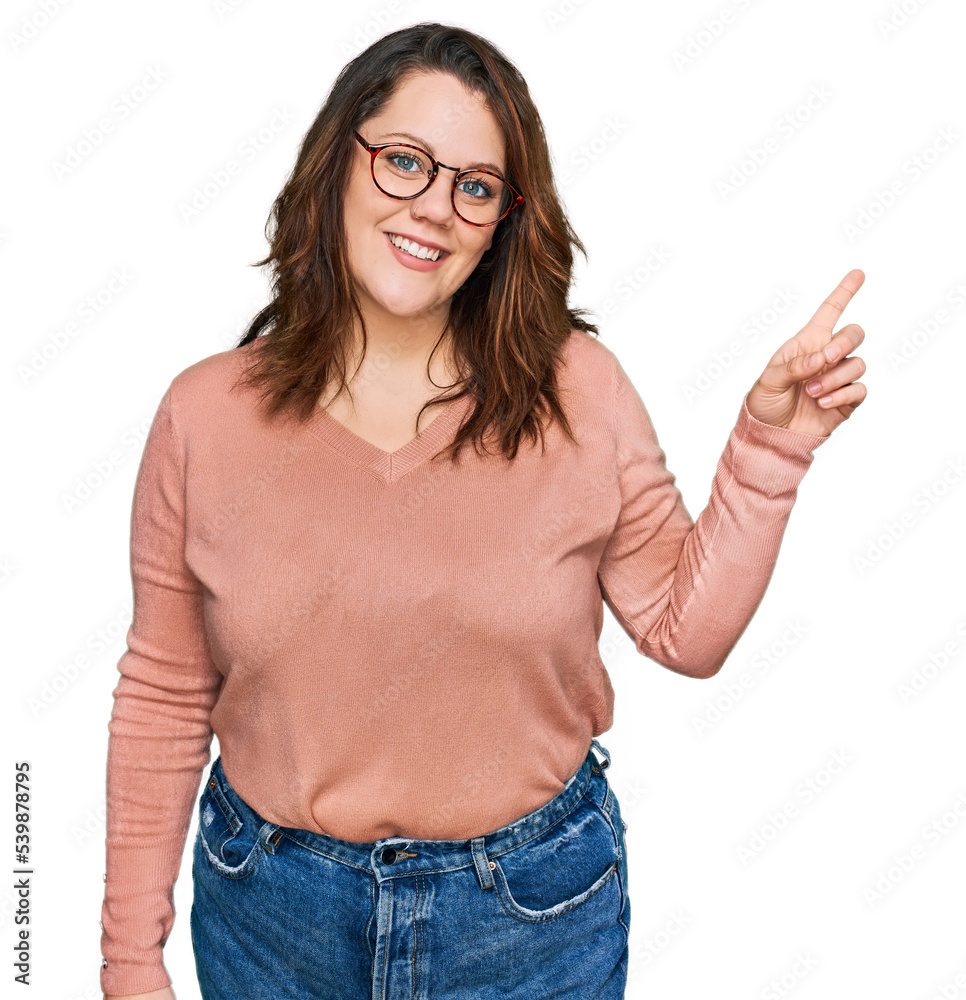 Young plus size woman wearing casual clothes and glasses with a big smile on face, pointing with hand finger to the side looking at the camera.