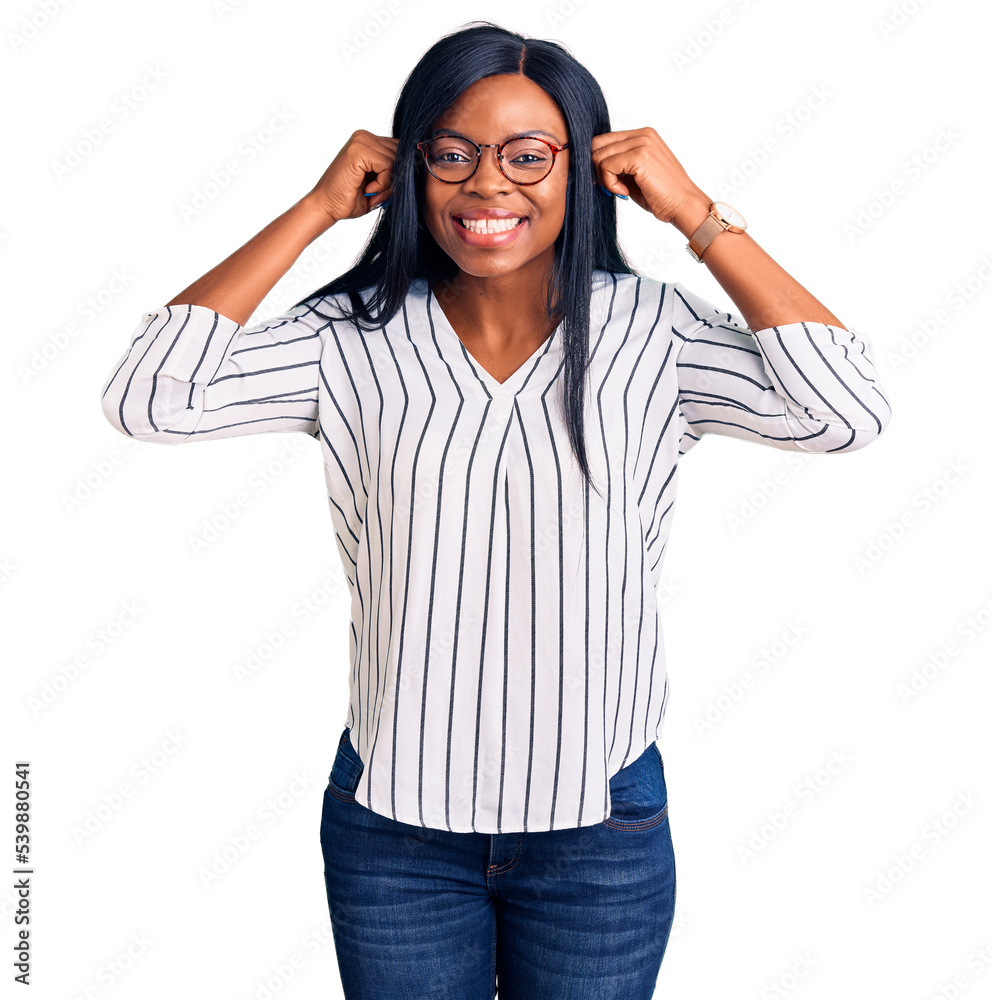 Young african american woman wearing casual clothes and glasses smiling pulling ears with fingers, funny gesture. audition problem Young african american woman wearing casual clothes and glasses smiling pulling ears with fingers, funny gesture. audition problem