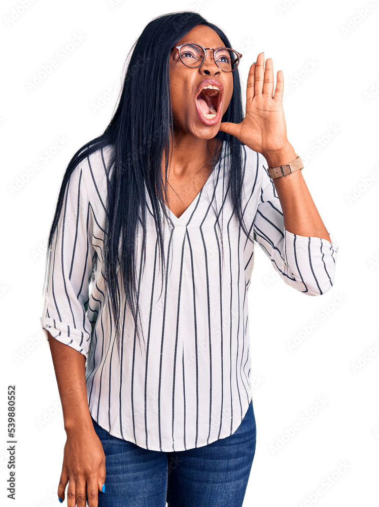 Φωτογραφία Young african american woman wearing casual clothes and glasses shouting and screaming loud to side with hand on mouth