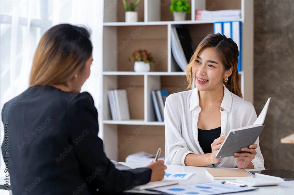 Two young Asian businessmen talk and discuss financial information. and the details planned by happily jotting down notes in a book... Two young Asian businessmen talk and discuss financial information. and the details planned by happily jotting down notes in a book...