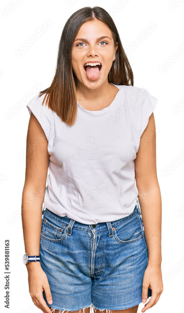 Obraz premium Young caucasian woman wearing casual white tshirt sticking tongue out happy with funny expression. emotion concept.