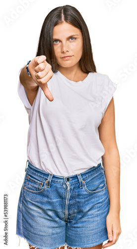 Young caucasian woman wearing casual white tshirt looking unhappy and angry showing rejection and negative with thumbs down gesture. bad expression.