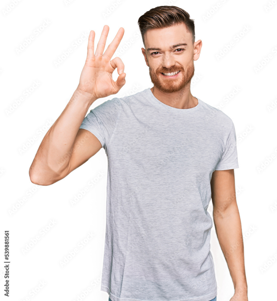Fototapeta premium Young redhead man wearing casual grey t shirt smiling positive doing ok sign with hand and fingers. successful expression.