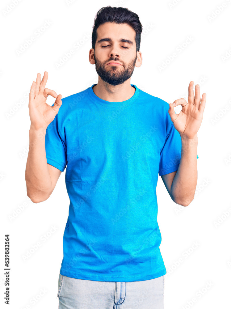 Young handsome man with beard wearing casual t-shirt relaxed and smiling with eyes closed doing meditation gesture with fingers. yoga concept. Young handsome man with beard wearing casual t-shirt relaxed and smiling with eyes closed doing meditation gesture with fingers. yoga concept.