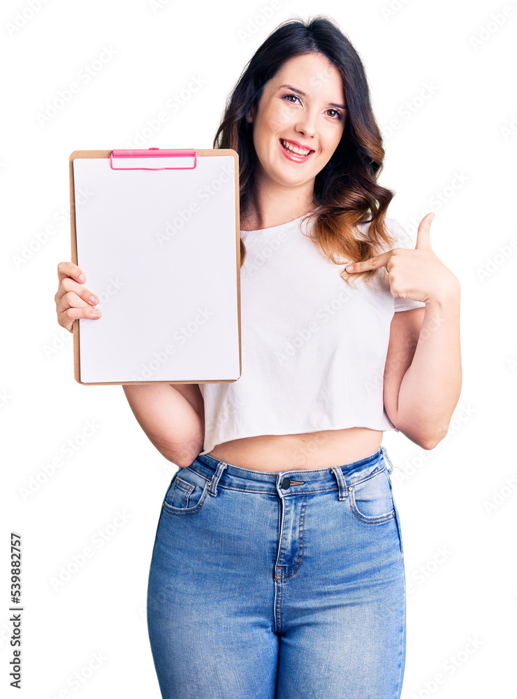 Beautiful young brunette woman holding clipboard with blank space pointing finger to one self smiling happy and proud Beautiful young brunette woman holding clipboard with blank space pointing finger to one self smiling happy and proud