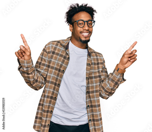 Young african american man with beard wearing casual clothes and glasses smiling confident pointing with fingers to different directions. copy space for advertisement