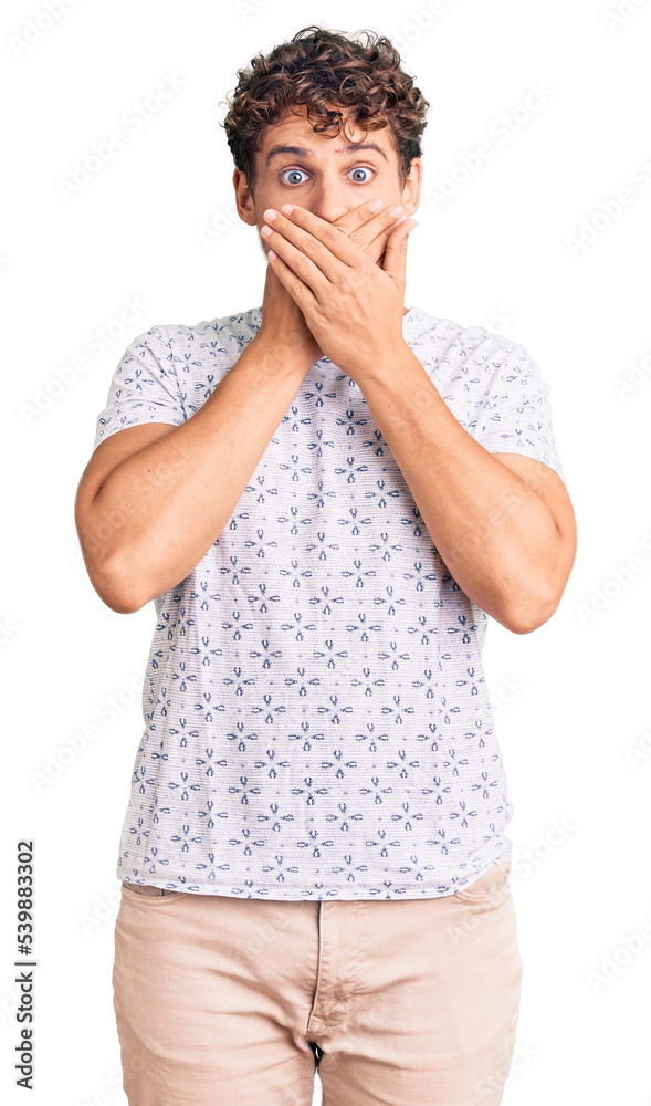 Young handsome man with curly hair wearing casual clothes shocked covering mouth with hands for mistake. secret concept.