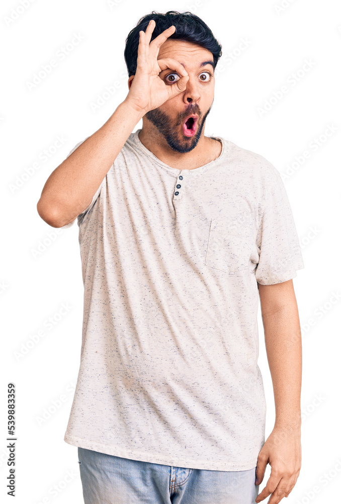 Young hispanic man wearing casual clothes doing ok gesture shocked with surprised face, eye looking through fingers. unbelieving expression. Young hispanic man wearing casual clothes doing ok gesture shocked with surprised face, eye looking through fingers. unbelieving expression.