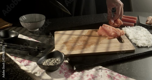 Chef slices salmon and prepares sushi