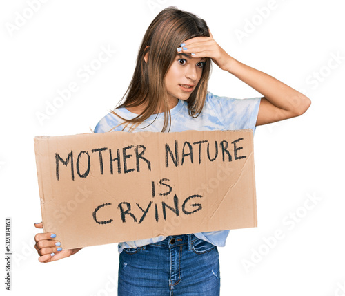Teenager caucasian girl holding mother nature is crying protest cardboard banner stressed and frustrated with hand on head, surprised and angry face