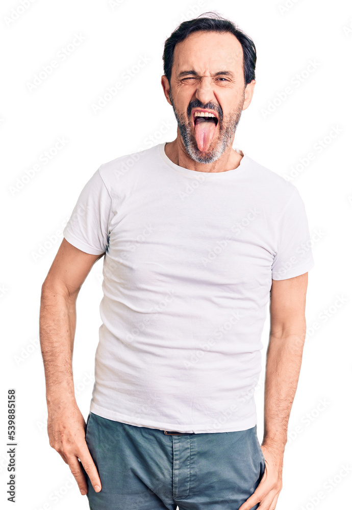 Obraz premium Middle age handsome man wearing casual t-shirt sticking tongue out happy with funny expression. emotion concept.