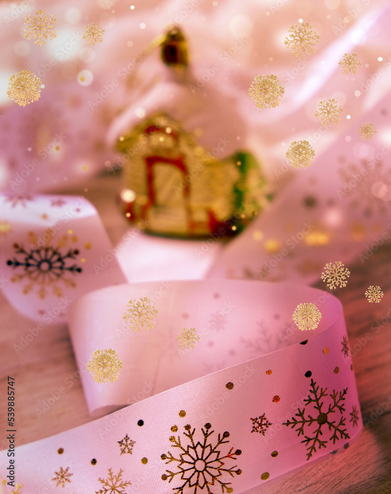 Minimal Christmas still life with golden white decorations ribbon and blurred house figurine on snowy background Minimal Christmas still life with golden white decorations ribbon and blurred house figurine on snowy background
