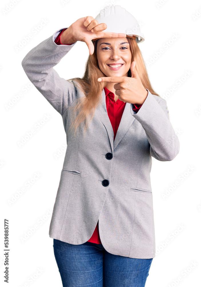 Beautiful young woman wearing architect hardhat smiling making frame with hands and fingers with happy face. creativity and photography concept. Beautiful young woman wearing architect hardhat smiling making frame with hands and fingers with happy face. creativity and photography concept.