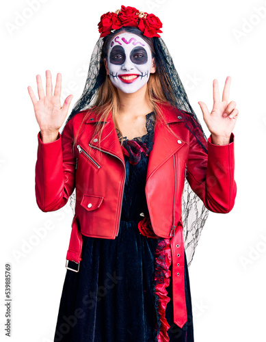 Woman wearing day of the dead costume over background showing and pointing up with fingers number eight while smiling confident and happy.
