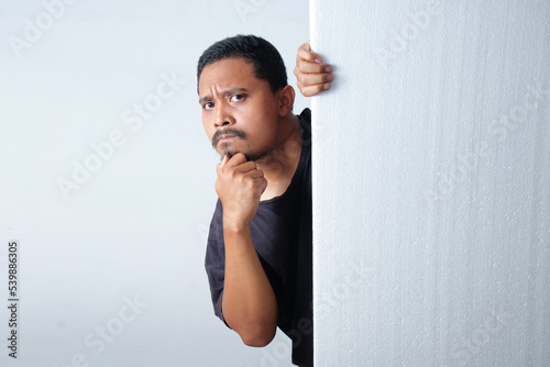 funny curious man peek behind wall