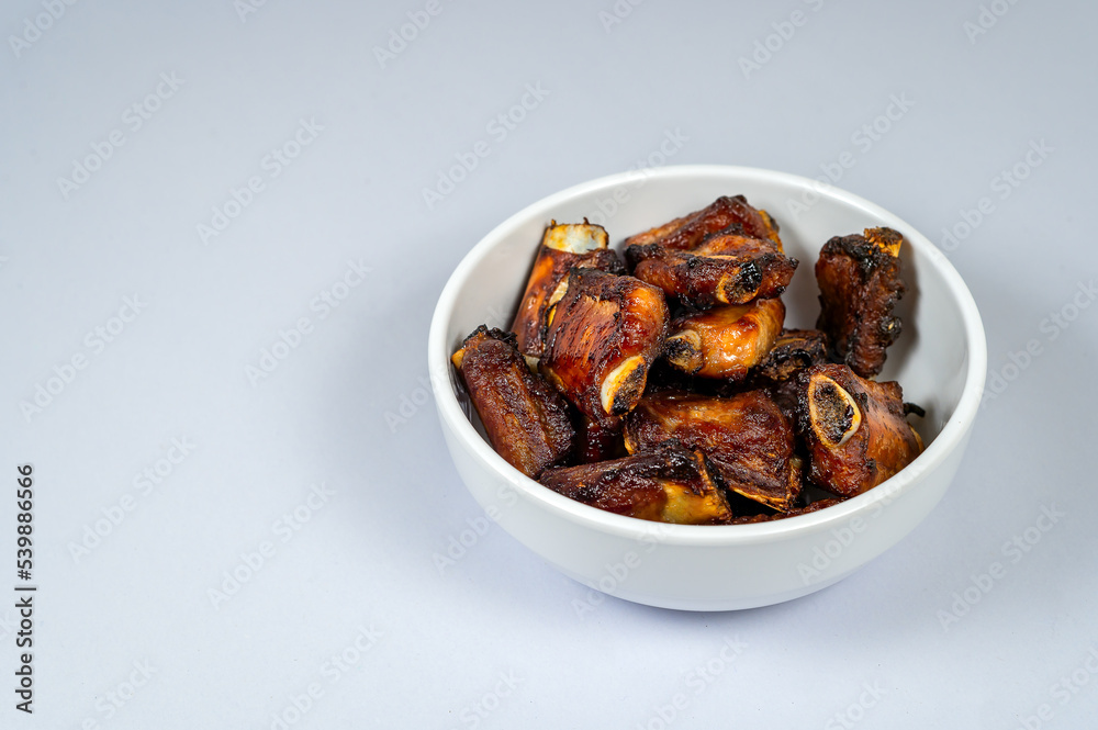 Grilled pork ribs in a bowl with white background, Obesity causes, Cancer causes, Unhealthy food. Grilled pork ribs in a bowl with white background, Obesity causes, Cancer causes, Unhealthy food.