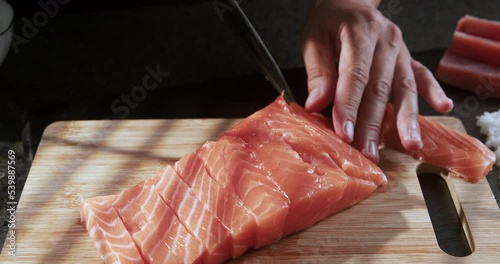 Chef slices salmon and prepares sushi