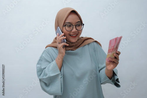 happy woman talking on phone while holding indonesian money photo