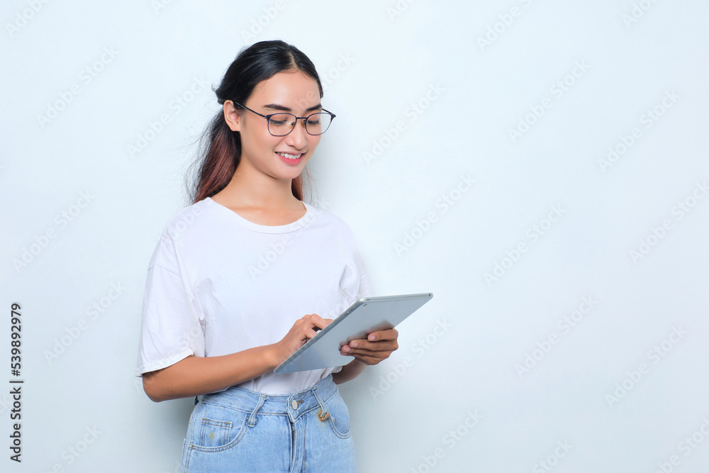 Portrait of smiling young Asian girl in white t-shirt using digital tablet isolated on white background