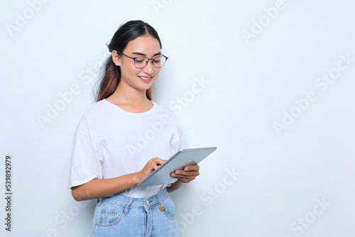 Portrait of smiling young Asian girl in white t-shirt using digital tablet isolated on white background