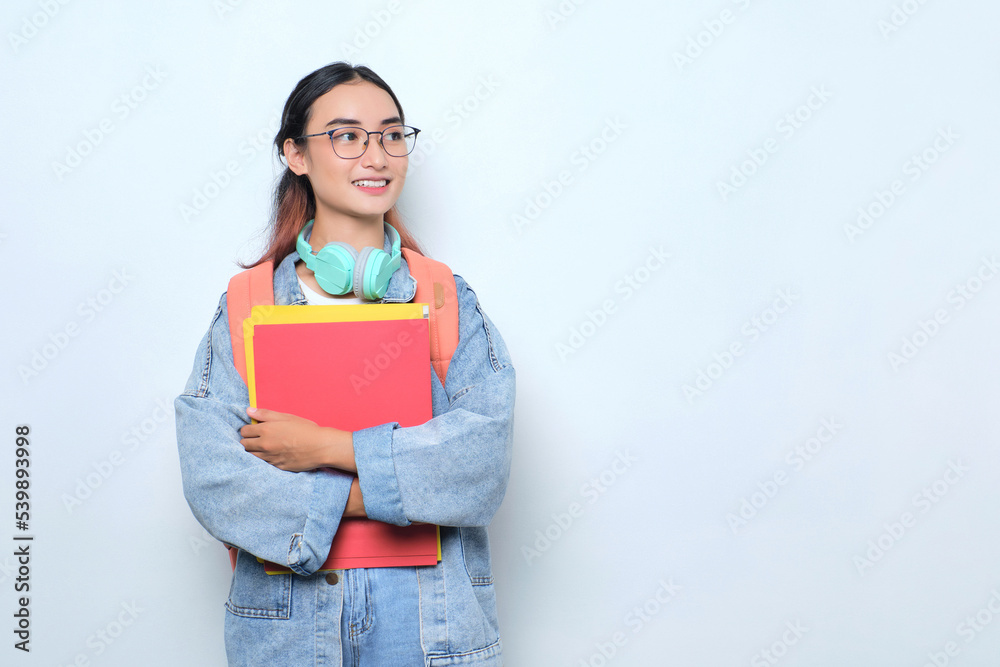 Smiling young pretty woman wearing a backpack holding books isolated on white background Smiling young pretty woman wearing a backpack holding books isolated on white background