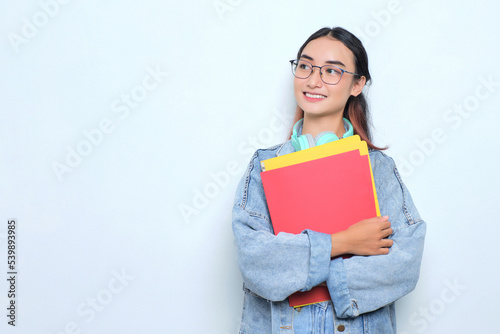 Smiling young pretty woman wearing a backpack holding books isolated on white background