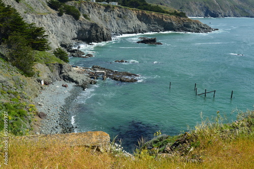 Black sand beach and blue-green water looking down the cliffs along the Pacific coast north of San Francisco.