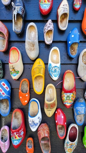 wooden shoes, Old wooden Dutch shoes - klomps. A lot of colorful old clomps against the background of a wooden wall. Popular souvenirs. Traditions of Holland. Background