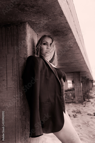 Vászonkép a woman dressed in a bodysuit and jacket stands leaning on a concrete ramp with