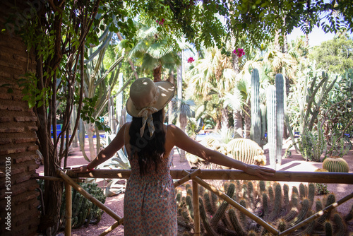 Schilderij op canvas Young and beautiful tourist with hat visiting and enjoying the Majorelle Berber garden which is a botanical garden in Marrakech (Morocco) designed by the French artist Jacques Majorelle