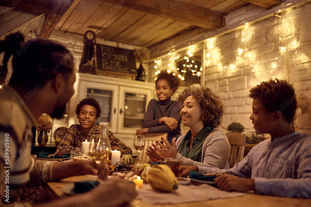 Happy black extended family talking while celebrating Thanksgiving at dining table.