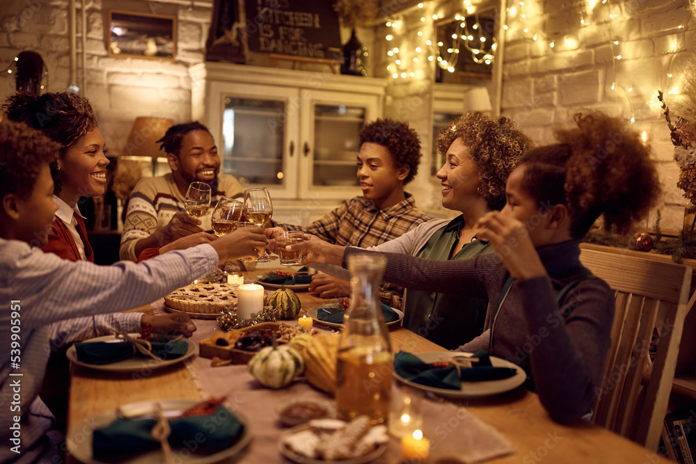 Happy African American extended family toasting during Thanksgiving dinner at dining table.