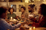 Black extended family saying grace during Thanksgiving dinner at dining table.