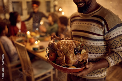 Close up of African American man serving Thanksgiving turkey during family dinner.